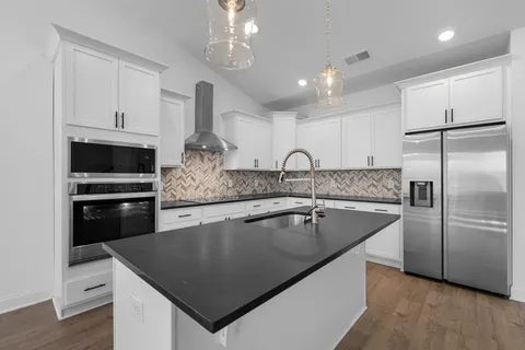 a kitchen with stainless steel appliances granite countertop a sink a stove and a refrigerator