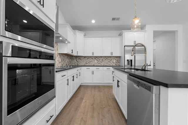 a kitchen with granite countertop a sink stainless steel appliances and cabinets