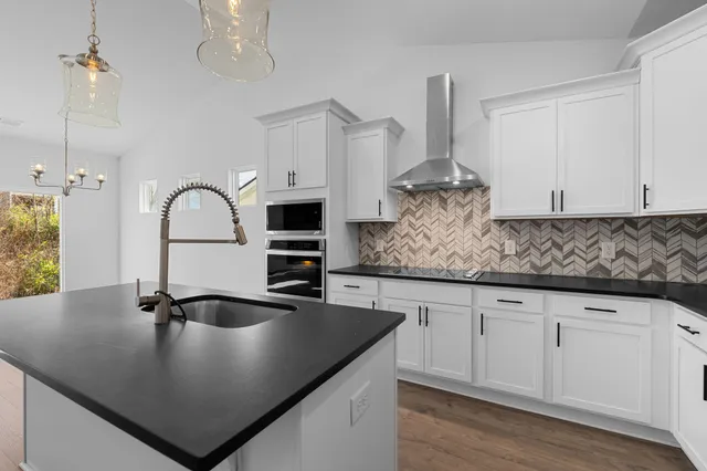 a kitchen with stainless steel appliances granite countertop a sink a stove and white cabinets