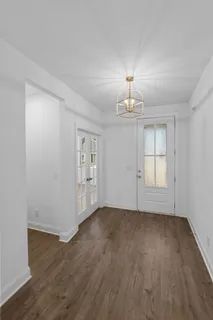 an empty room with wooden floor chandelier and windows