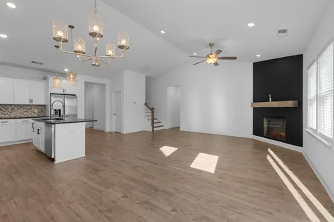 a large kitchen with kitchen island granite countertop a stove a sink a refrigerator and a fireplace