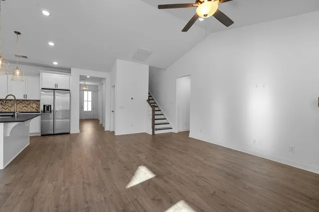 a view of an empty room with a kitchen and a window
