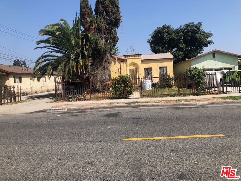 a view of a house with a yard and palm trees