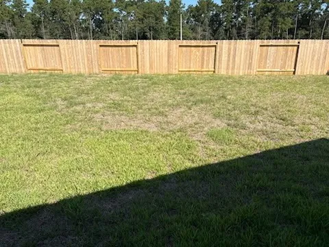 a view of large yard with wooden fence