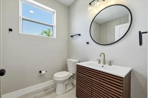 a bathroom with a sink a mirror a toilet and a window
