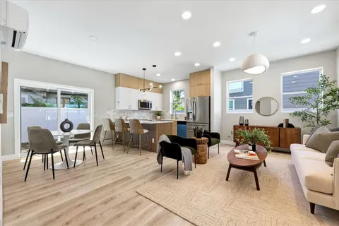 a living room with furniture kitchen view and a large window