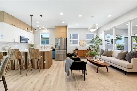 a living room with furniture kitchen view and a large window