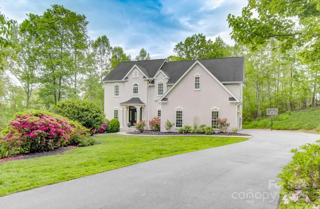 a view of a white house with a big yard and large trees