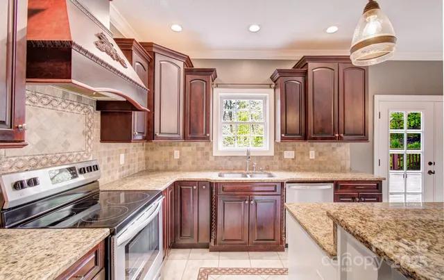 a kitchen with granite countertop kitchen island stainless steel appliances a sink stove and cabinets