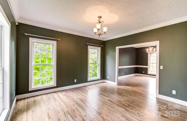 a view of an empty room with window and wooden floor