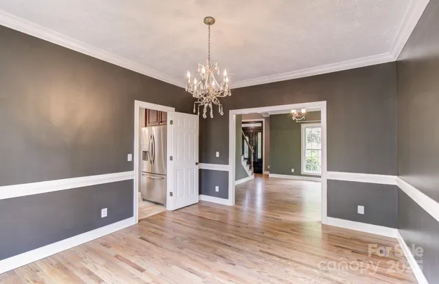 a view of a room with wooden floor and chandelier