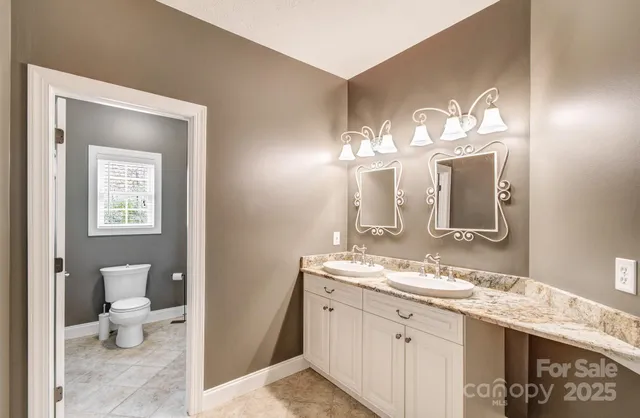 a bathroom with a granite countertop sink mirror and toilet