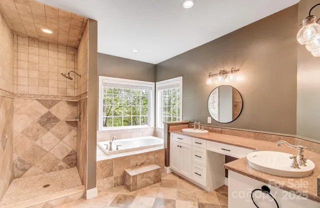 a bathroom with a double vanity sink a mirror a bathtub and shower