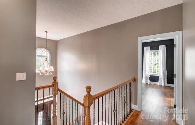 a view of a hallway with wooden floor and stairs