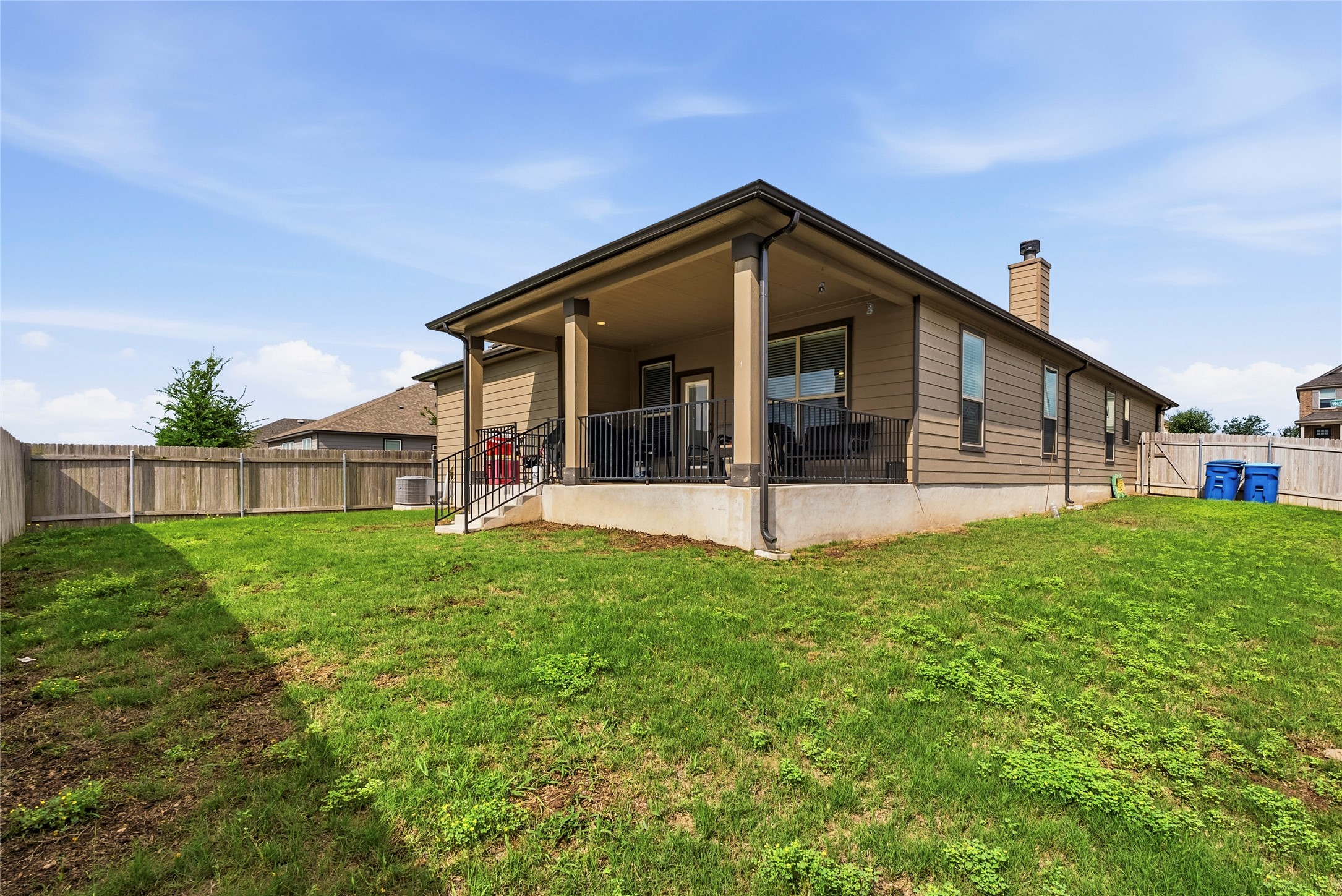 105 West Point Way Elgin, TX 78621 - Photo 15 of 27 Expansive backyard featuring a covered patio, black metal railings, and a wooden privacy fence