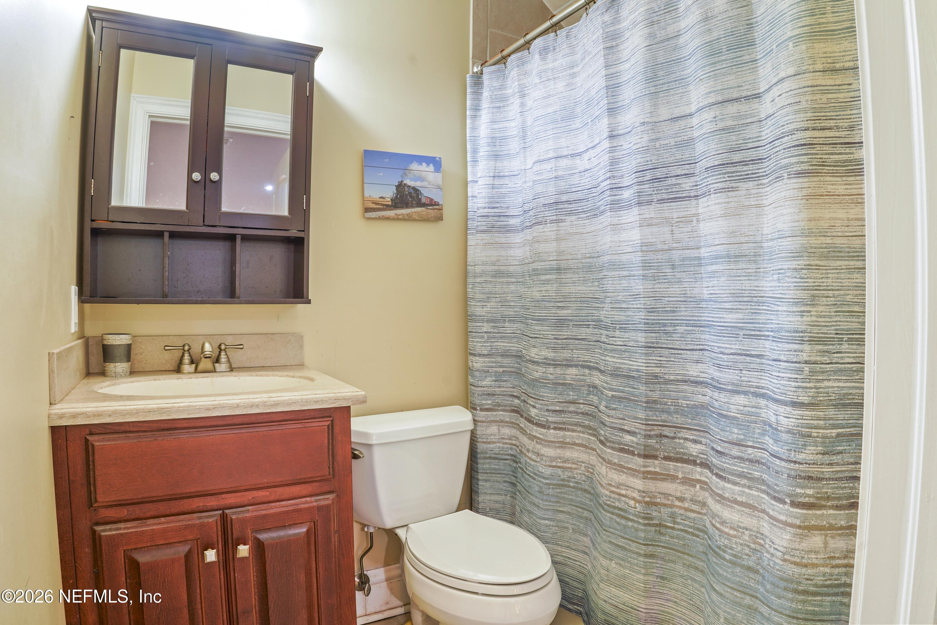 6153 Tim Crews Road Macclenny, FL 32063 - Photo 58 of 79 a bathroom with a toilet a sink a vanity and mirror