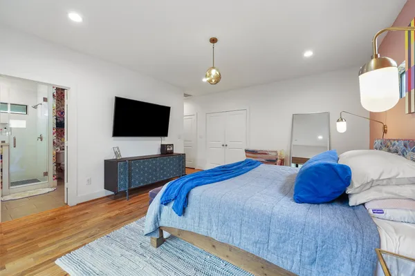 a bedroom with a bed and a flat tv screen on dresser