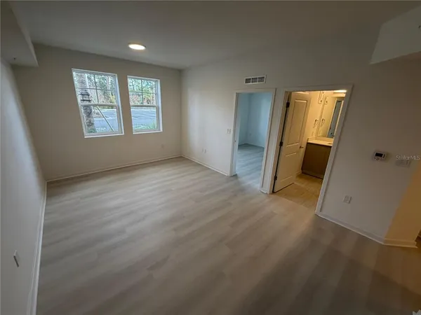 an empty room with wooden floor and windows