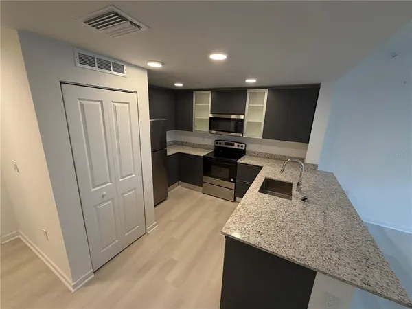 a living room with stainless steel appliances furniture a refrigerator and a counter top