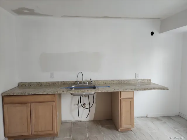 a utility room with stainless steel appliances granite countertop a sink and a white cabinets