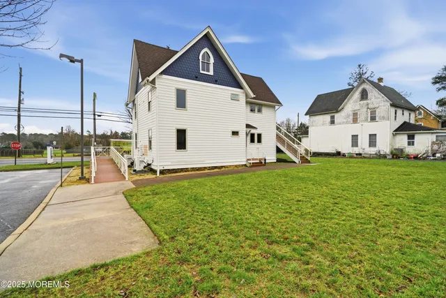 a view of a white house next to a yard with big trees