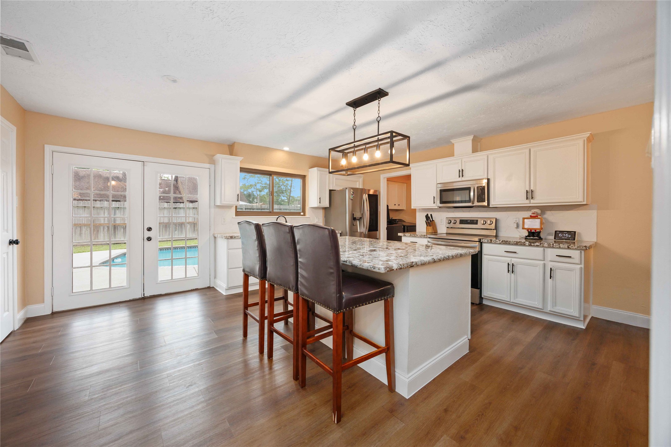 7310 Hickory Lane Baytown, TX 77521 - Photo 8 of 17 a kitchen with stainless steel appliances granite countertop a refrigerator a stove top oven a sink dishwasher and white cabinets with wooden floor