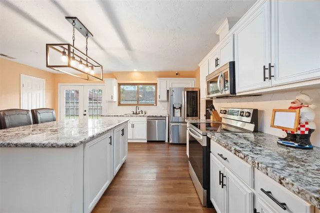 a large kitchen with stainless steel appliances granite countertop a lot of counter space and a sink