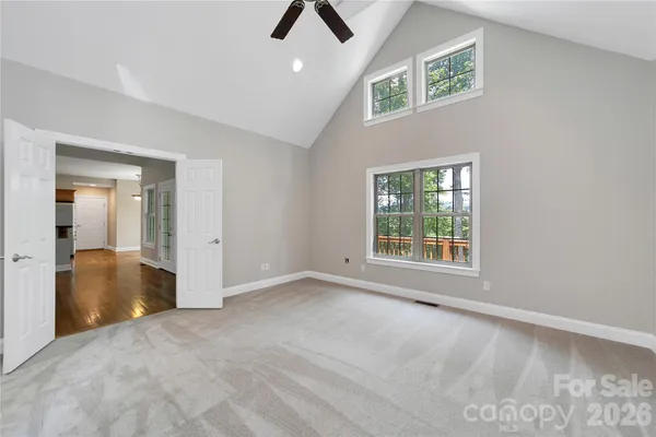 a view of an empty room with chandelier fan and fire place