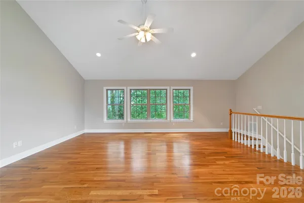 a view of empty room with wooden floor and fan