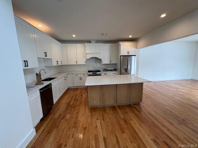 11 Colonels Path Manorville, NY 11949 - Photo 15 of 49 Kitchen with a kitchen island, stainless steel fridge, light wood finished floors, black dishwasher, and two tone cabinets