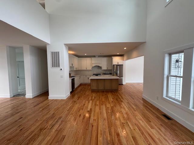 11 Colonels Path Manorville, NY 11949 - Photo 48 of 49 Great room with high ceilings opens up to Kitchen with open floor plan, light countertops, stainless steel refrigerator with ice dispenser, and recessed lighting and 2 tone cabinets