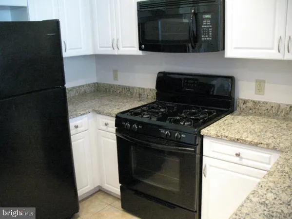 a kitchen with granite countertop white cabinets and black appliances