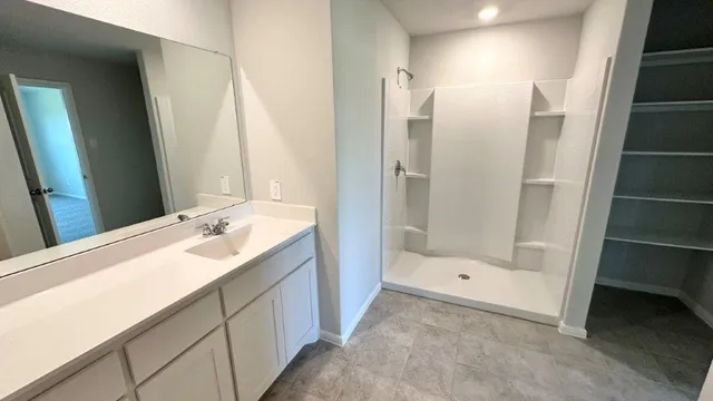 a view of an empty room with kitchen and window