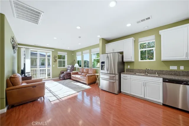 a living room with stainless steel appliances granite countertop furniture and a wooden floor