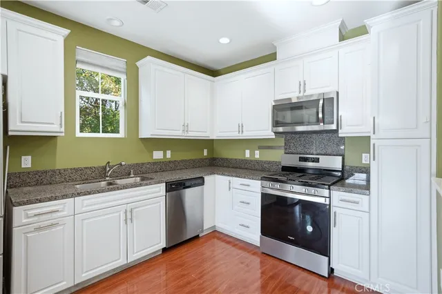 a kitchen with stainless steel appliances granite countertop a sink stove and microwave
