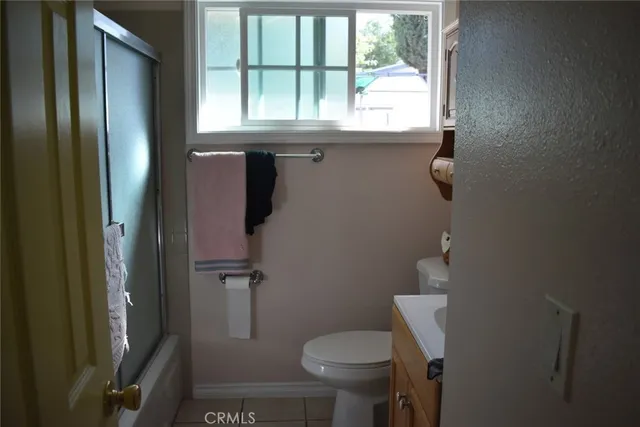 a bathroom with a granite countertop toilet a sink and a window