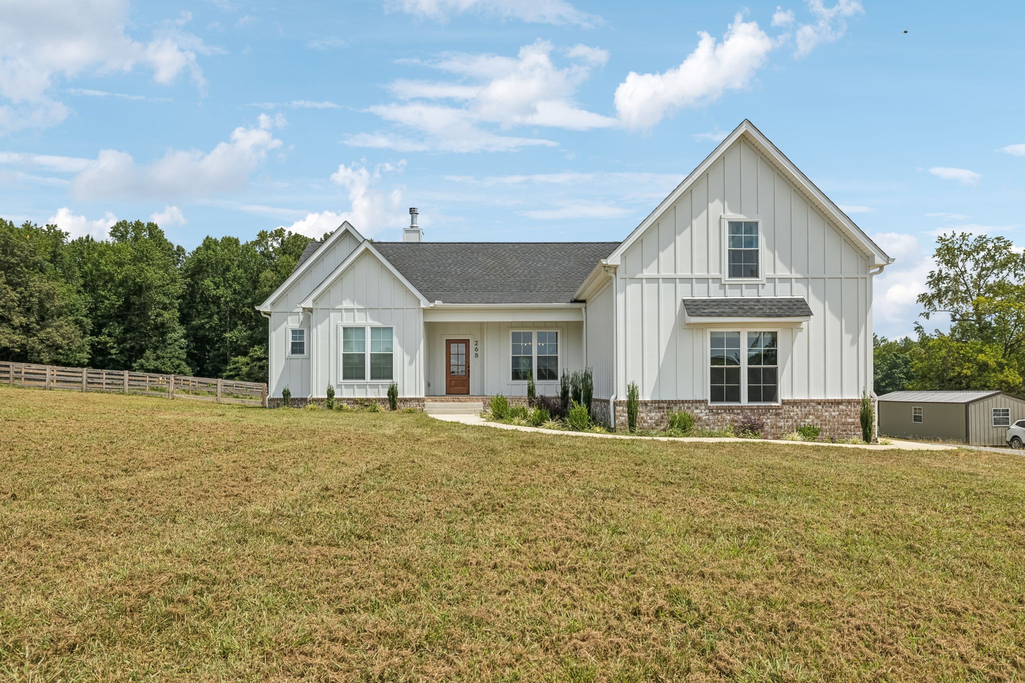 a front view of house with yard and trees in the background
