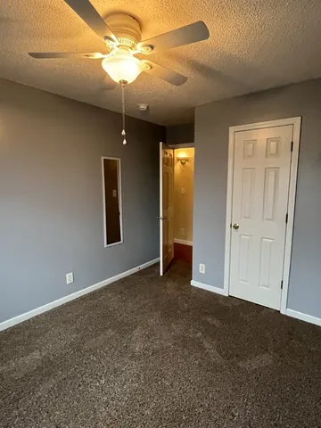 an empty room with closet and a chandelier fan