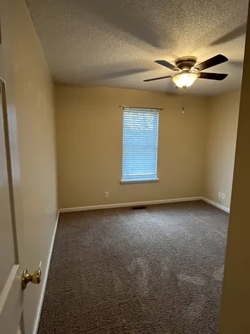 an empty room with windows and fan