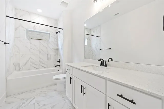 a bathroom with a granite countertop sink a toilet and shower
