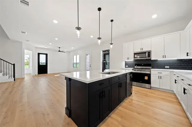 a large kitchen with stainless steel appliances kitchen island granite countertop a stove a sink and a refrigerator