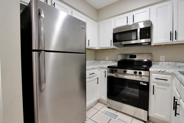 a kitchen with granite countertop a sink dishwasher stove and microwave with wooden cabinets
