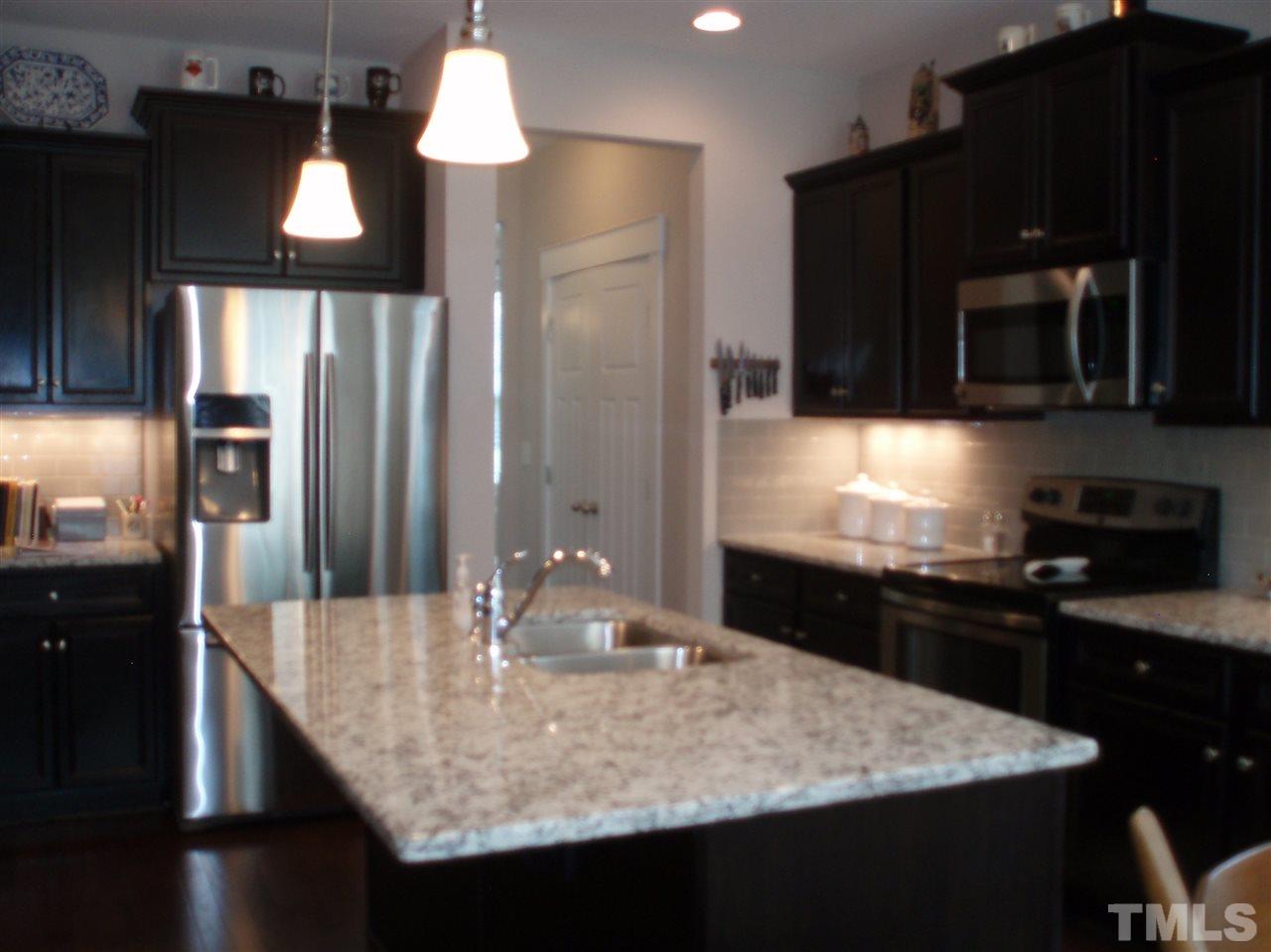 6108 Spring Branch Circle Raleigh, NC 27603 - Photo 4 of 20 a kitchen with kitchen island granite countertop a sink and refrigerator