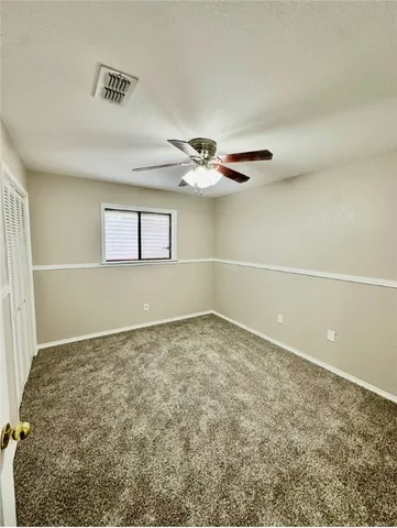 an empty room with closet and a chandelier fan