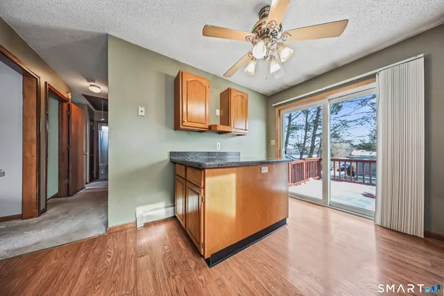 a kitchen with stainless steel appliances granite countertop a stove top oven a refrigerator a sink and a dining table with wooden floor