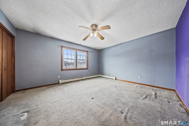 an empty room with windows and ceiling fan