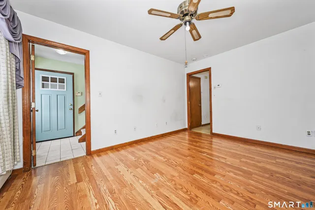 a view of empty room with wooden floor and fan