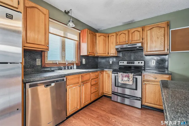 a kitchen with stainless steel appliances granite countertop a stove a sink and white cabinets