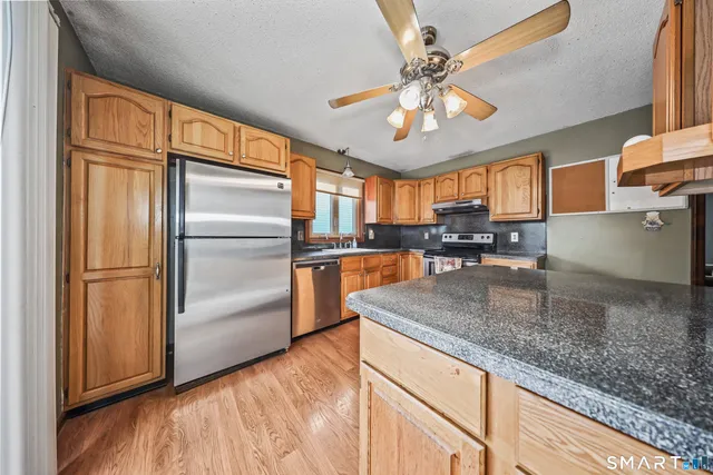 a kitchen with stainless steel appliances granite countertop a refrigerator a sink a stove and island