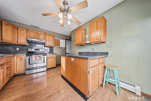 a large kitchen with stainless steel appliances granite countertop a stove a sink dishwasher and a refrigerator with wooden floor